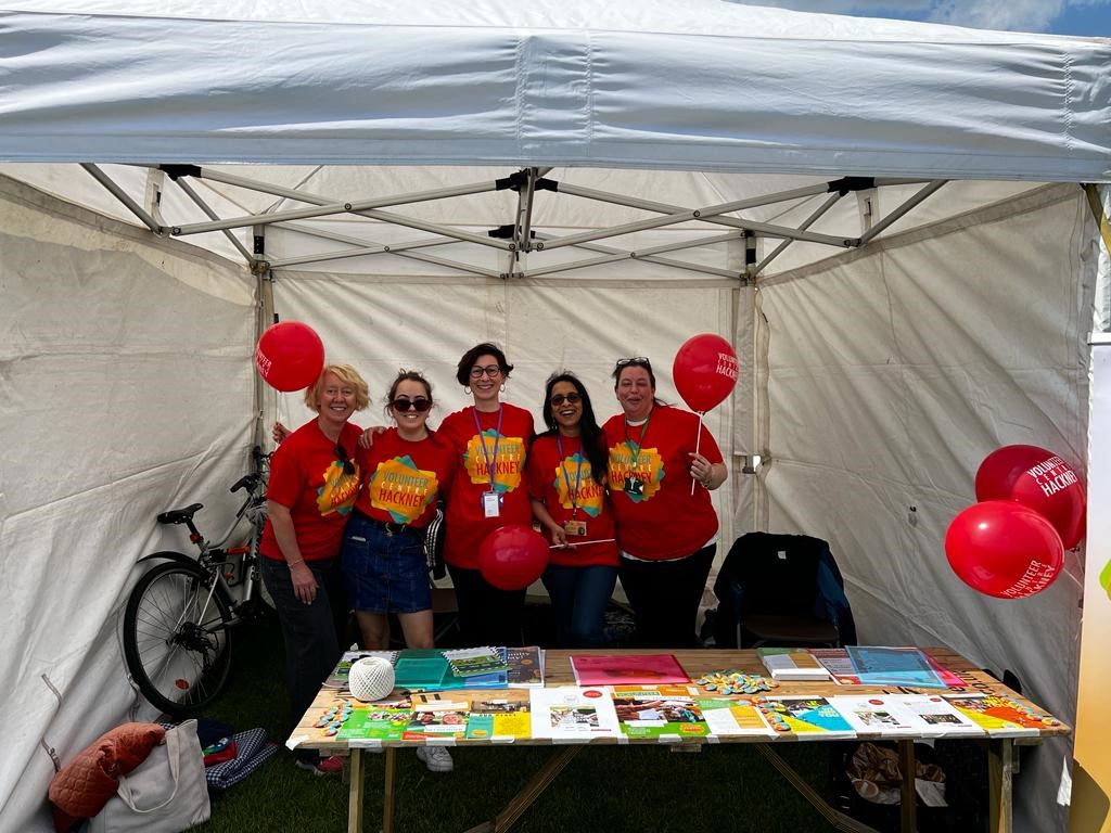 Group of VCH staff grinning at Hackney Half Marathon stand, wearing VCH t-shirts and balloons
